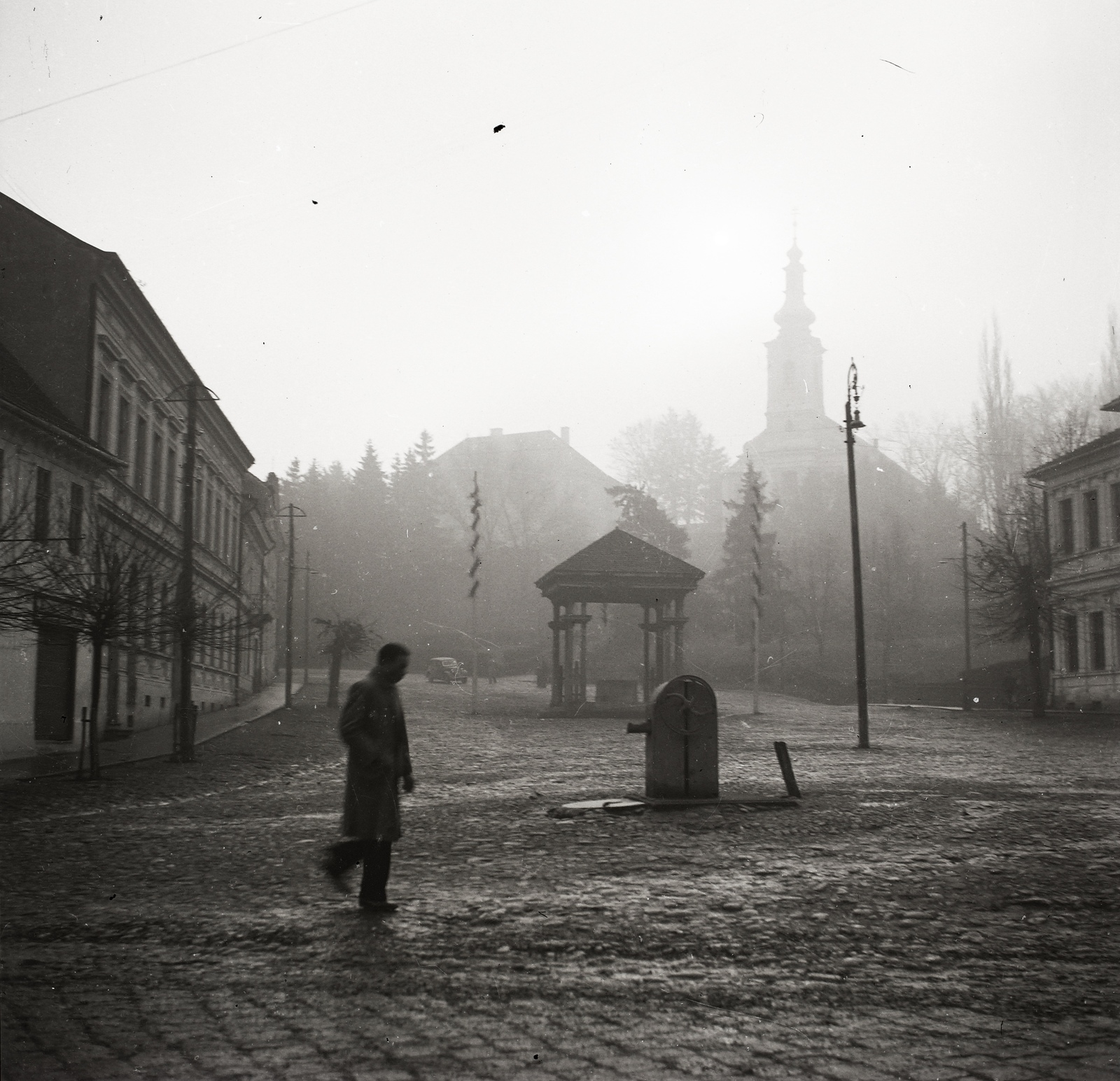 Romania,Transylvania, Ordorheiu Secuiesc, Márton Áron (Deák) tér, a tölgyfaoszlopokon nyugvó galambdúcos zsindelytető alatti talapzaton egykor a Vas Székely szobor állt, az első világháború hősi halottainak emlékére. Távolban a Szent Miklós-templom., 1940, Ebner, church, silhouette, Fortepan #83902