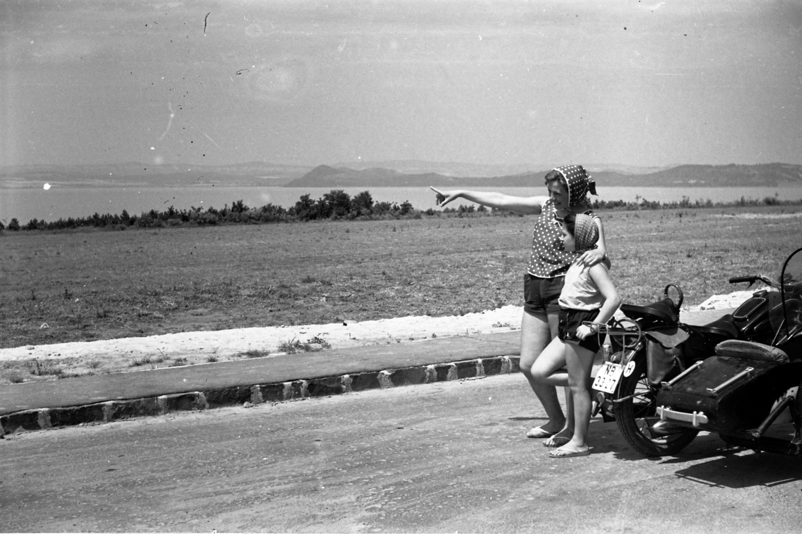 Hungary, Balatonföldvár, háttérben a Tihanyi-félsziget., 1960, Morvay Kinga, Morvay Lajos, Soviet brand, Izh-brand, motorcycle with sidecar, headscarf, number plate, country code sign, arms around shoulders, Fortepan #84385