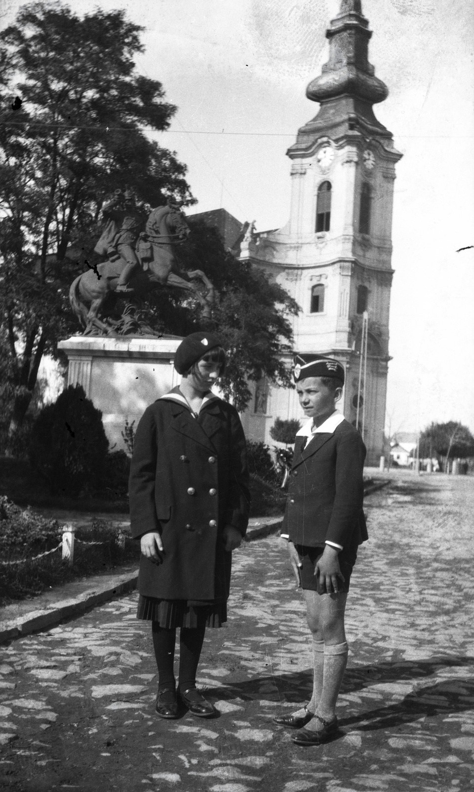 Magyarország, Jászberény, Lehel vezér (Apponyi Albert) tér, a Jász huszárok első világháborús emlékműve (Pongrácz Szigfrid, 1926.), mögötte a Nagyboldogasszony-templom., 1936, Morvay Kinga, Morvay Lajos, templom, egyenruha, szobor, lovas szobor, Fortepan #84506