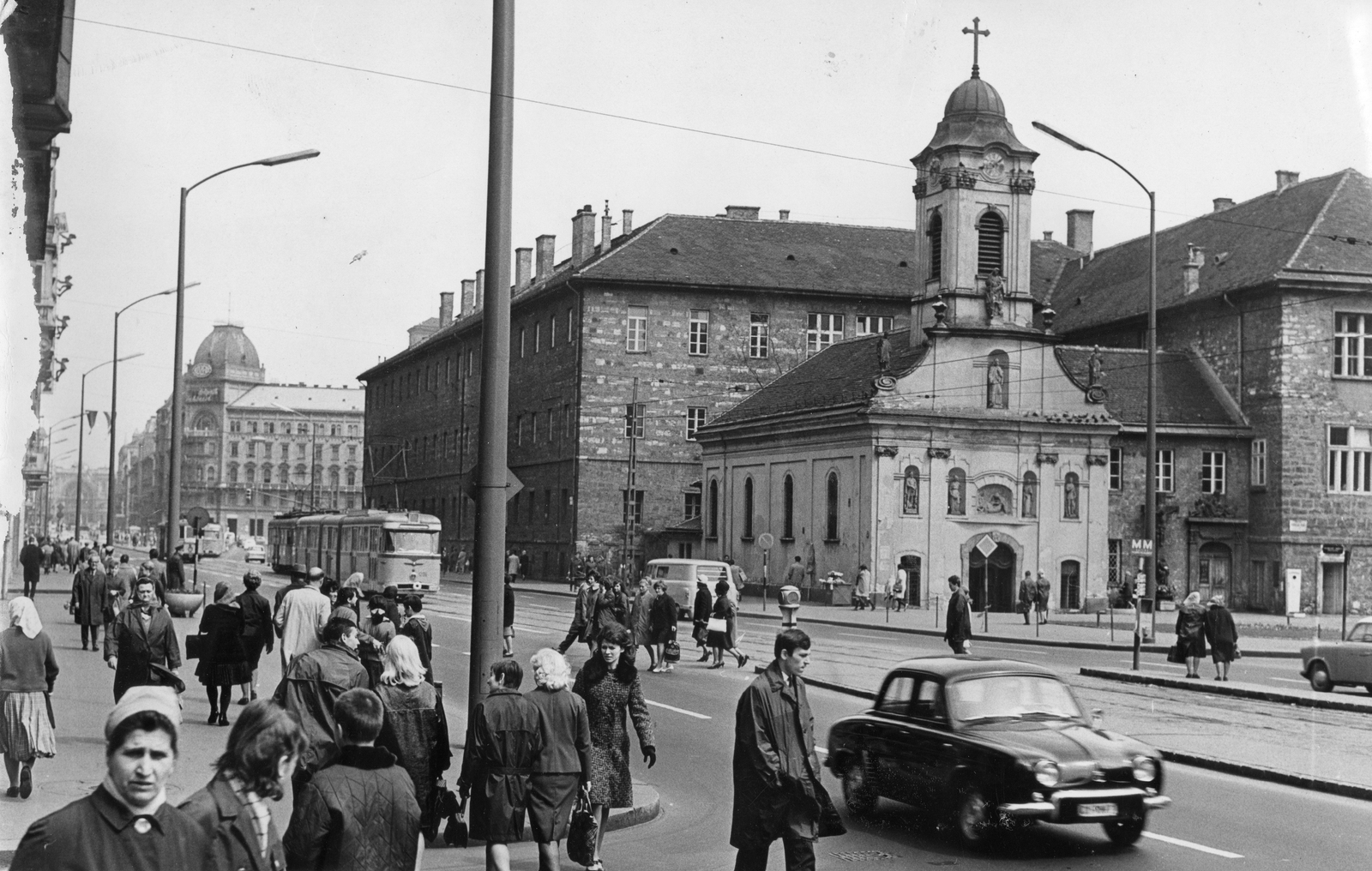 Hungary, Budapest VIII., Rákóczi út a Nagy Diófa utcától a Nagykörút felé nézve. Szemben a Szent Rókus-kápolna, mögötte a Rókus kórház., 1967, Magyar Hírek folyóirat, church, traffic, pedestrian, street view, genre painting, tram, csibi lamp, nylon fabric jacket, tram stop, automobile, neon lights, Bengali tramway, Budapest, Fortepan #84634