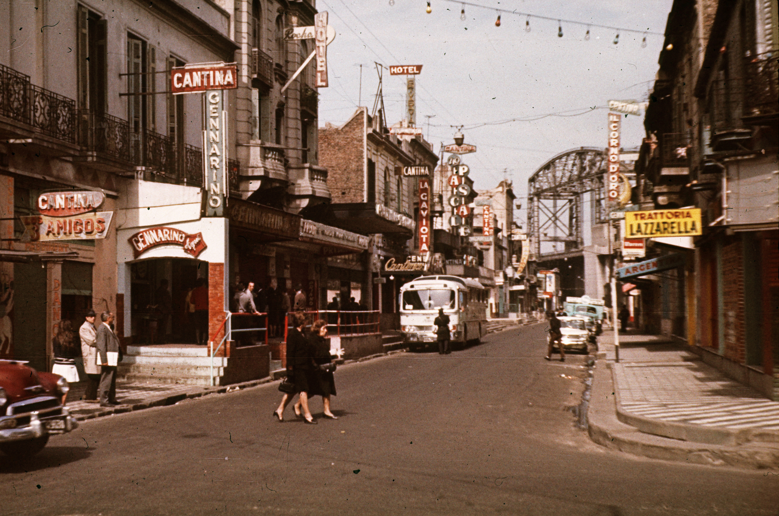 Argentína, Buenos Aires, Necochea a Suárez felől nézve. Az utca végénél a Matanza folyó hídja látszik., 1966, Métneki János dr, reklám, színes, autóbusz, cégtábla, járókelő, utcakép, életkép, automobil, Fortepan #85097