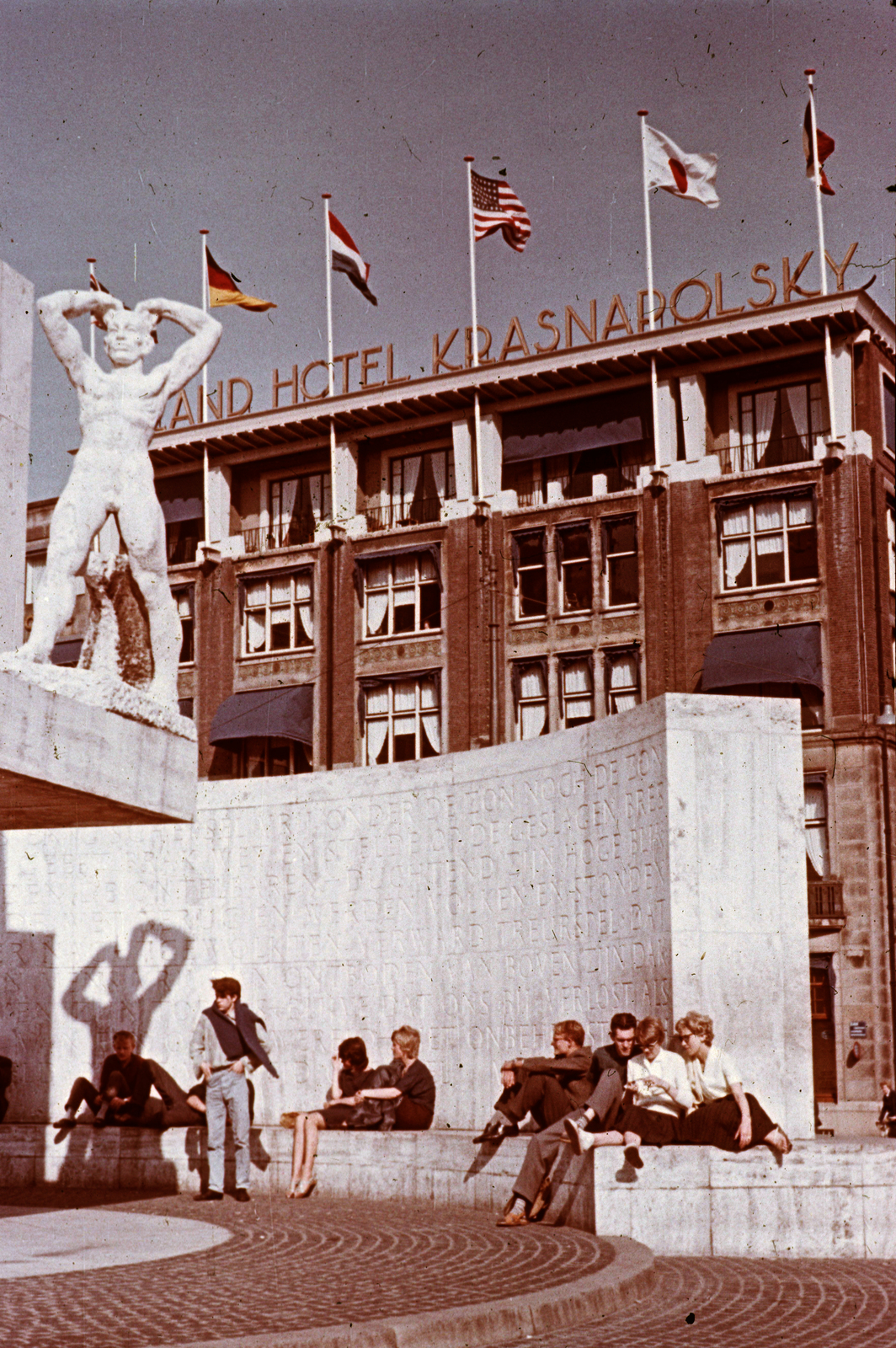 Netherlands, Amsterdam, Dam tér, Nemzeti Emlékmű, háttérben a Hotel Krasnapolsky., 1962, Métneki János dr, colorful, flag, sculpture, hotel, shadow, nude figure, Fortepan #85116