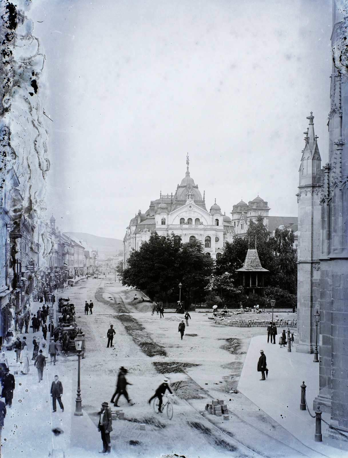 Szlovákia, Kassa, Fő tér (Hlavné namestie), Állami Színház, háttérben jobbra a Szentháromság-templom a Dómtól nézve., 1906, Magyar Földrajzi Múzeum / Erdélyi Mór cége, kerékpár, templom, nemzeti színház, járókelő, kockakő, sérült kép, ácsolat, mérmű, Láng Adolf-terv, neobarokk stílus, Fortepan #86994