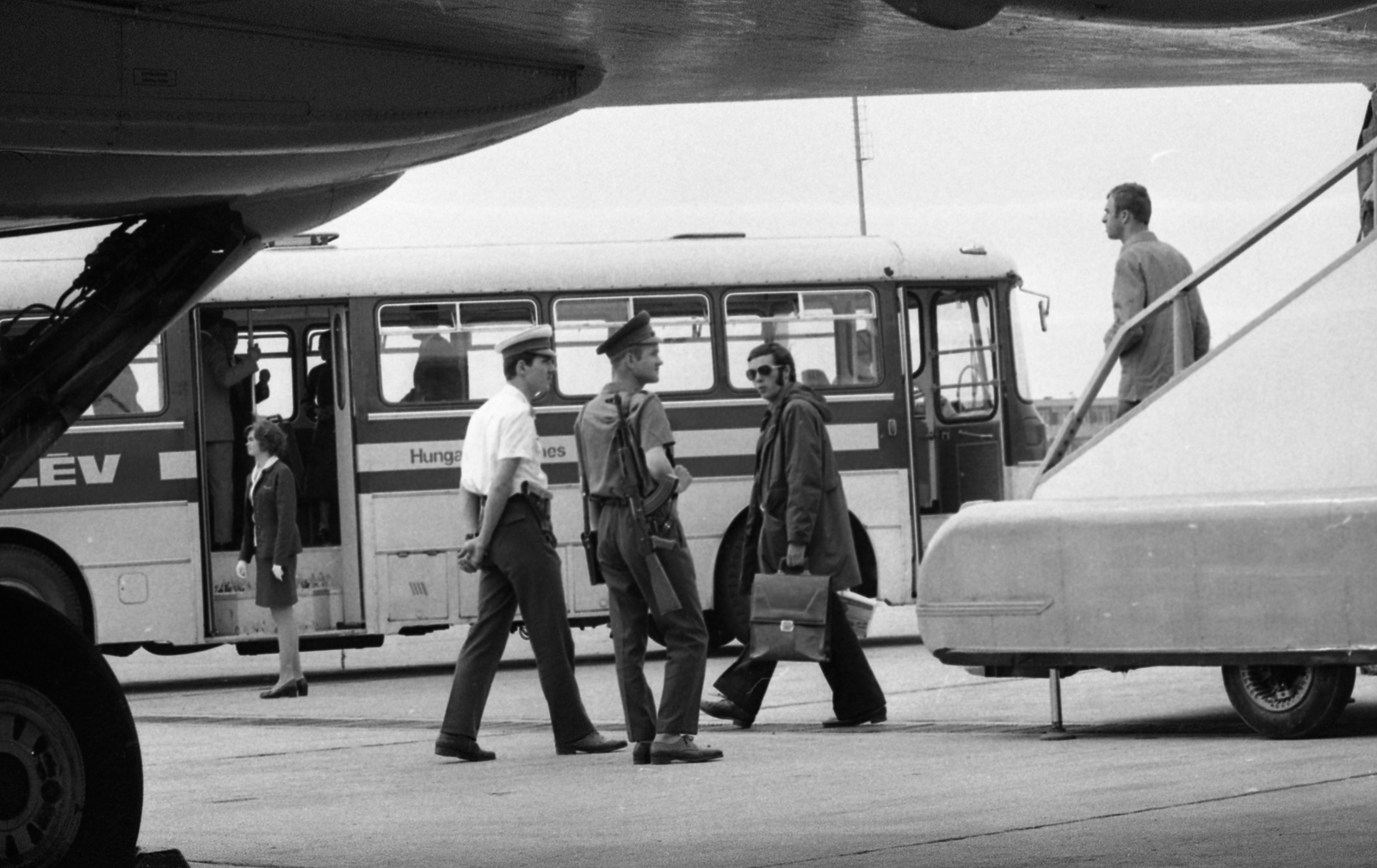 Hungary, Ferihegy (now - Ferenc Liszt) International Airport, Budapest XVIII., 1974, Urbán Tamás, bus, Hungarian brand, Ikarus-brand, cop, shades, Kalashnikov, weapon, airport, Hungarian Airlines, machine gun, border patrol, Budapest, aircraft steps, airport bus, Fortepan #88532