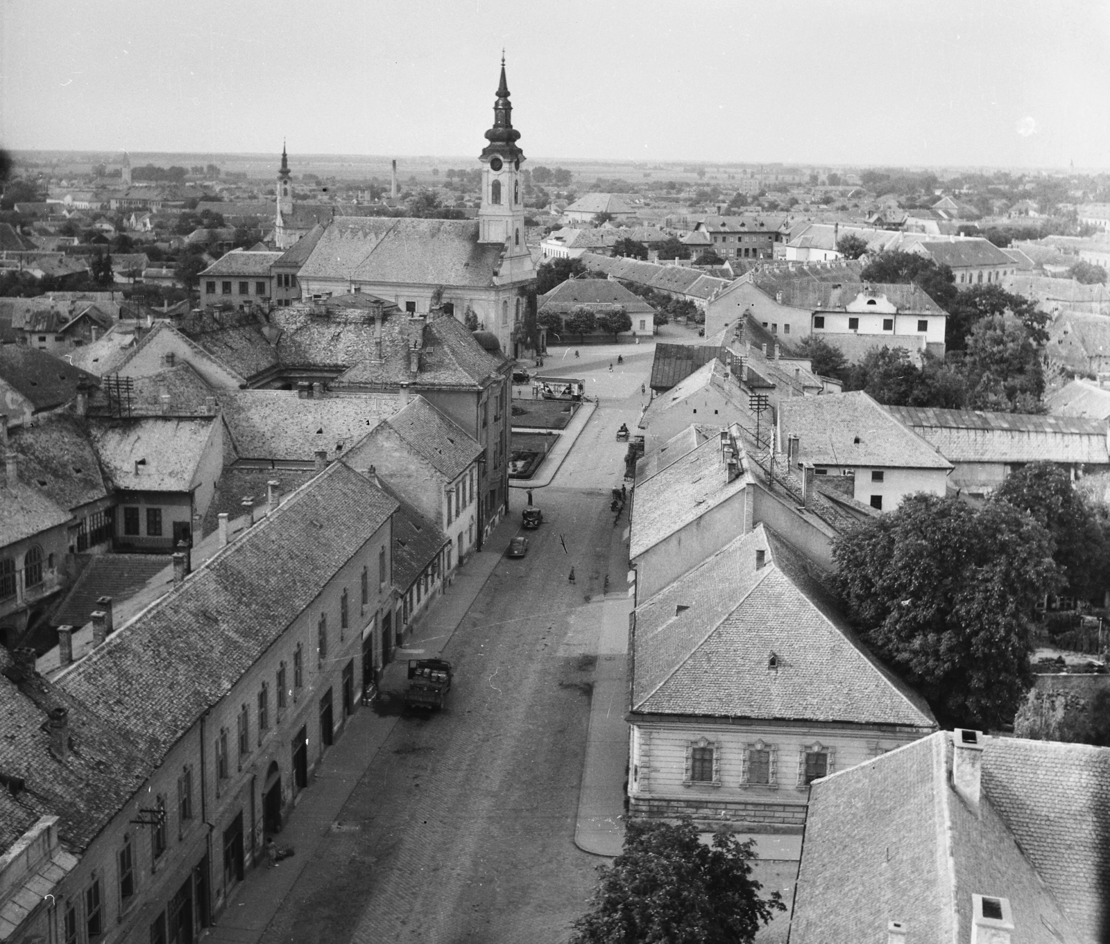 Hungary, Baja, Bartók Béla utca a Páduai Szent Antal-templom tornyából a Tóth Kálmán tér felé nézve. Szemben a Szent Péter és Pál apostolok templom, mögötte a Szent Miklós görögkeleti templom., 1955, UVATERV, egy dunai hajóút, picture, street view, roof, Fortepan #91049