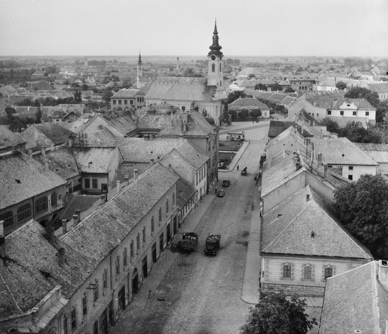 Hungary, Baja, Bartók Béla utca a Páduai Szent Antal-templom tornyából a Tóth Kálmán tér felé nézve. Szemben a Szent Péter és Pál apostolok templom, mögötte a Szent Miklós görögkeleti templom., 1955, UVATERV, egy dunai hajóút, street view, picture, roof, Fortepan #91050
