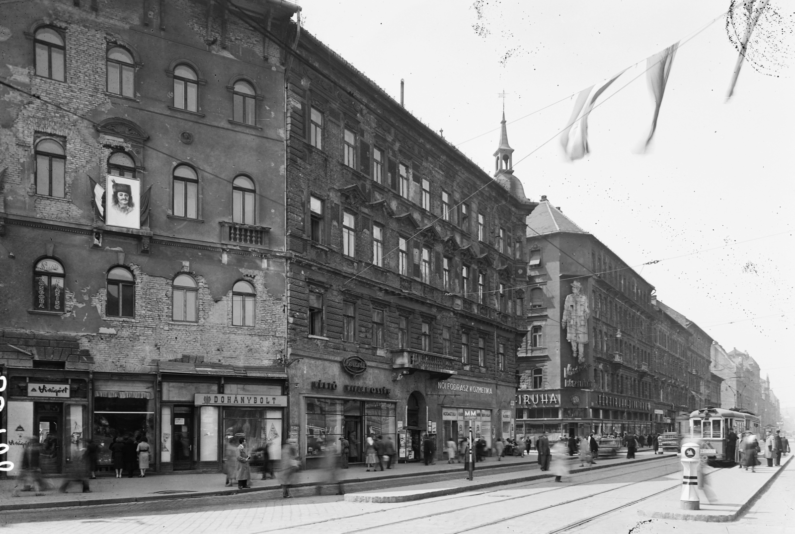 Hungary, Budapest VIII., Rákóczi út a Baross térről nézve, balra a Berzsenyi Dániel utca torkolata., 1957, UVATERV, sign-board, genre painting, neon sign, tram, tobacco shop, hairdresser, csibi lamp, tram stop, florist, Budapest, Fortepan #91336