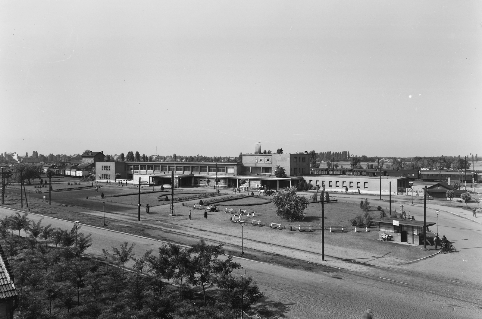 Hungary, Nyíregyháza, Állomás tér, vasútállomás, előtte a villamos és keskeny-nyomtávú vasút végállomás., 1960, UVATERV, bicycle, street view, genre painting, waiting, letter box, train station, train, modern architecture, narrow-gauge railway, cab-horse, Fortepan #91723