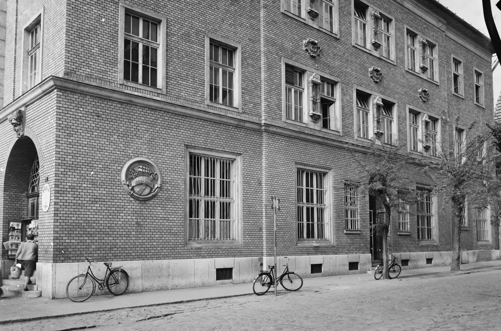 Hungary, Cegléd, a Kossuth Ferenc utcai Postapalota Gubody utcai homlokzata., 1963, UVATERV, bicycle, street view, post, memorial plaque, post office, window bars, brick covering, relief, Fortepan #91827