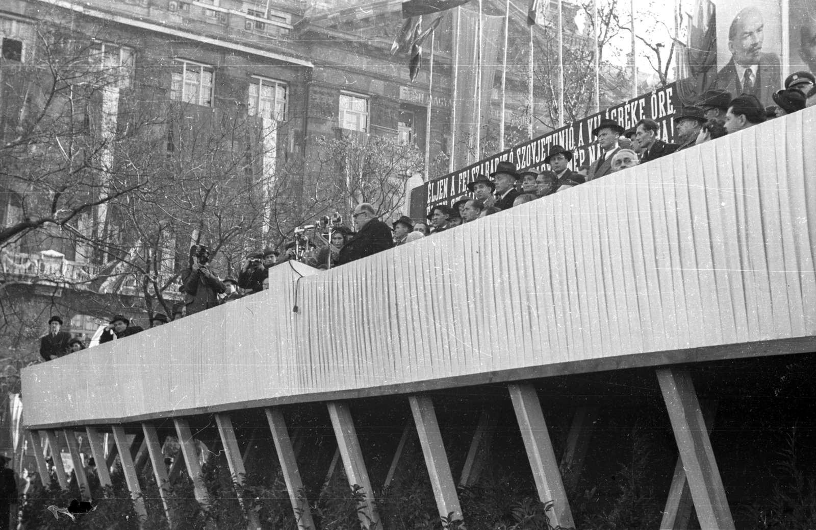 Magyarország, Budapest V., Széchenyi István (Roosevelt) tér, háttérben a mai Belügyminisztérium épülete. Az újjáépített Széchenyi Lánchíd ünnepségének tribünjén a mikrofonnál Bebrits Lajos közlekedésügyi miniszter., 1949, UVATERV, ünnepség, politika, politikai dekoráció, mikrofon, tribün, Budapest, Fortepan #92020