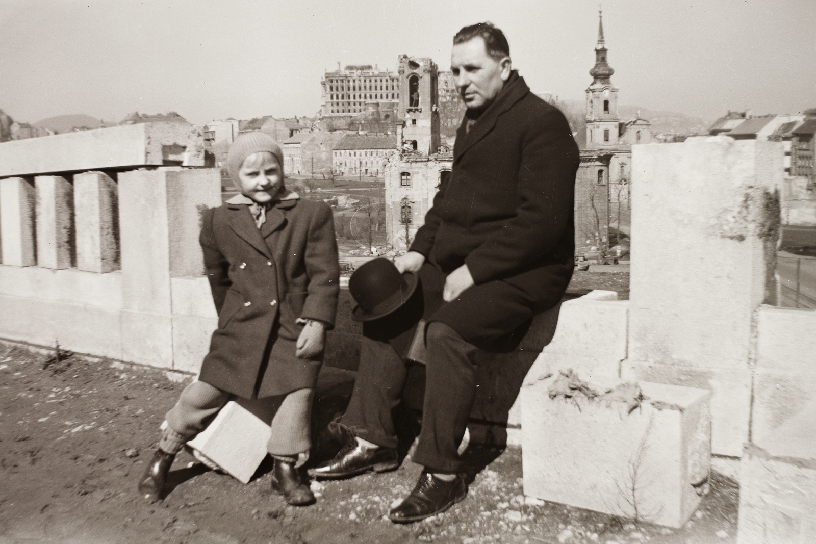 Magyarország, Gellérthegy, Budapest I., látkép a Szent Gellért szobortól a lerombolt szerb templom és a Királyi Palota (később Budavári Palota) felé nézve., 1946, Fortepan/Album002, háborús kár, épületkár, Budapest, sapka, úriember, falon ülni, kabát, kislány, keménykalap, Fortepan #92634