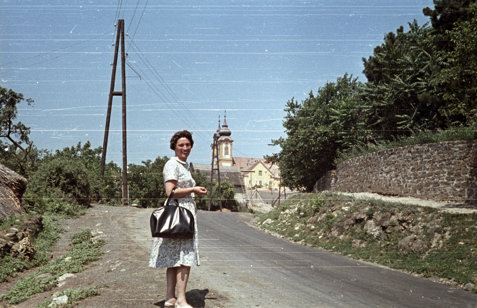 Hungary,Lake Balaton, Tihany, Kossuth Lajos utca, háttérben a Bencés Apátság., 1961, G K, church, colorful, Baroque-style, handbag, lady, sandal, monastery, summer dresses, Benedictines, Márton Wittwer-design, Fortepan #92833