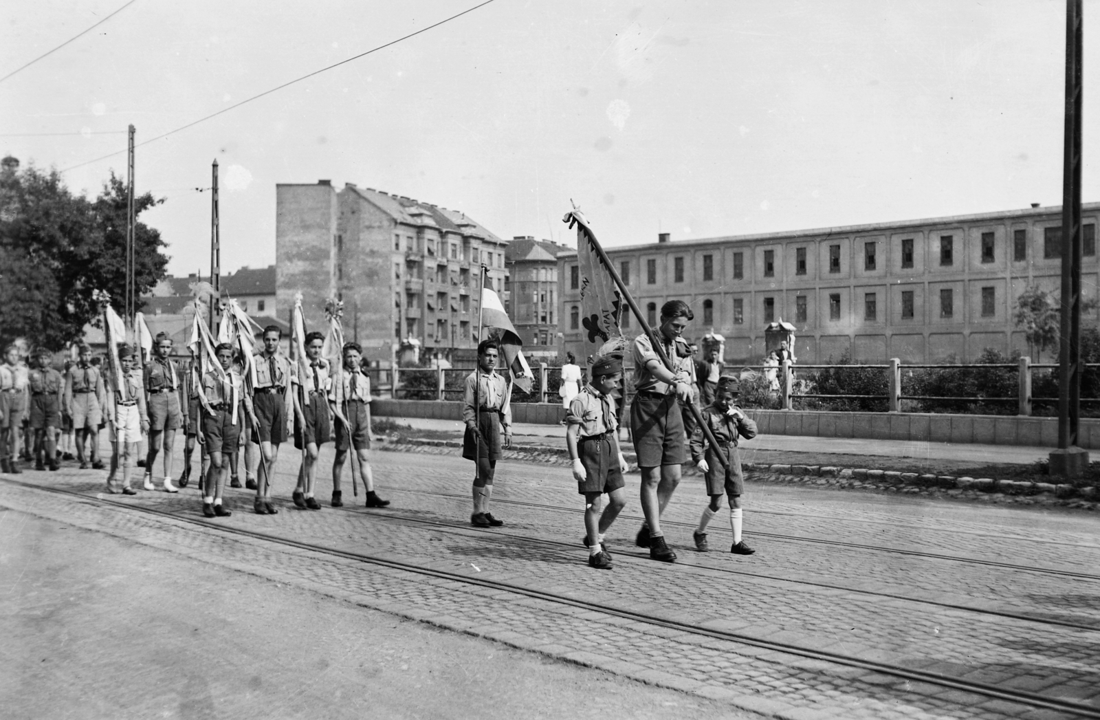 Magyarország, Budapest VIII., Simor (Vajda Péter) utca, jobbra a Golgota út (ekkor utca) mellett a Ganz gyár épülete. Balra a háttérben, keresztbe az Orczy út, szemben a két ház a Kőris utca torkolatánál áll., 1937, Kurutz Márton, zászló, felvonulás, cserkész, Budapest, Fortepan #93495