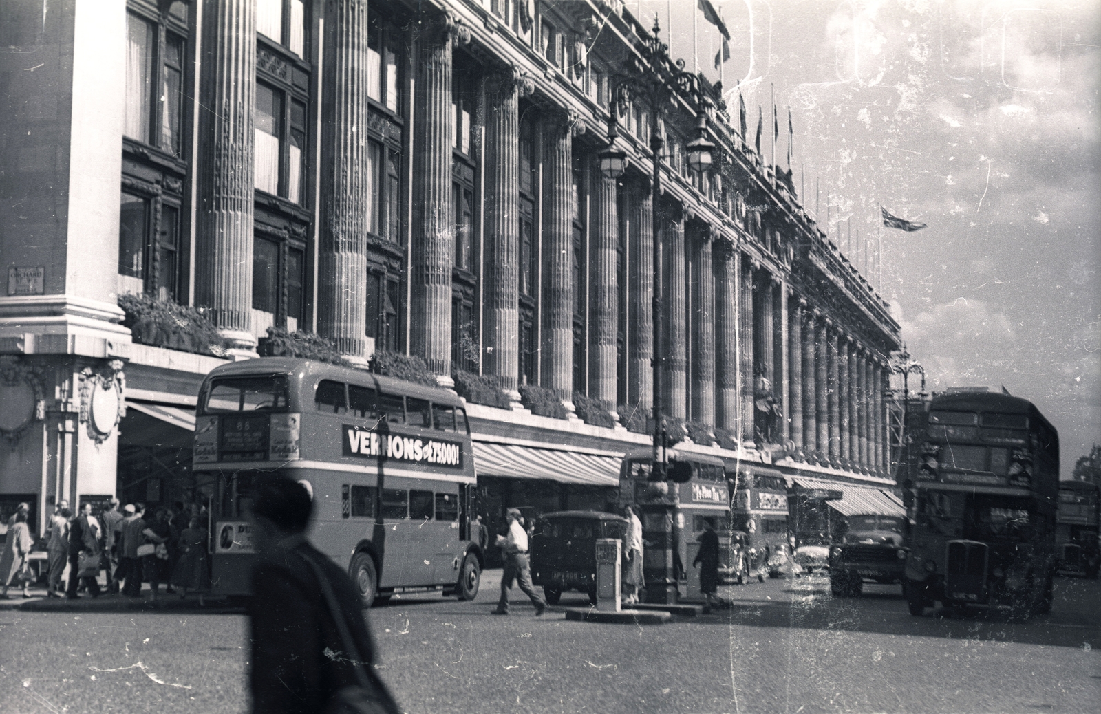 United Kingdom, London, Oxford Street, balra az Orchard Street sarka, szemben a Selfridges Áruház., 1957, Vaskapu utca, flag, pedestrian, commercial vehicle, street view, genre painting, double-decker, automobile, Fortepan #94473