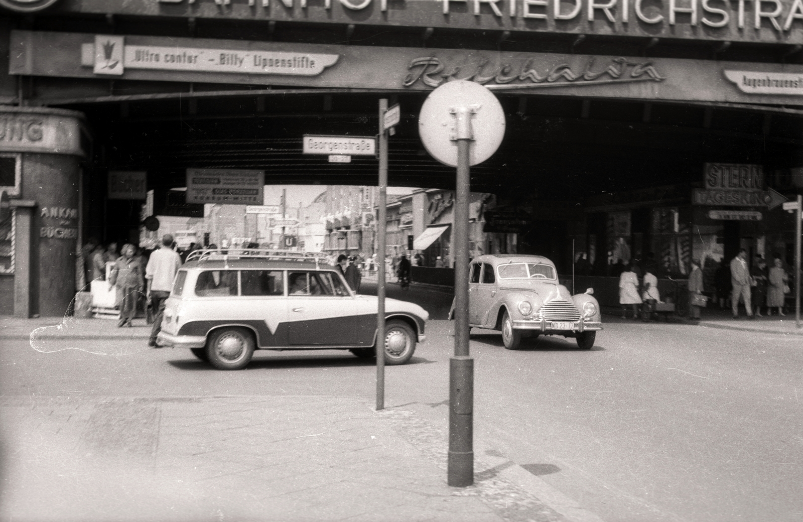 Németország, Berlin, Kelet-Berlin, Friedrichstrasse, balra a Georgenstrasse, fent a Friedrichstrasse pályaudvar., 1957, Vaskapu utca, reklám, cégtábla, járókelő, utcakép, életkép, EMW-márka, NDK, utcanévtábla, Kelet-Berlin, AWZ-márka, AWZ P70 Zwickau, Fortepan #94484