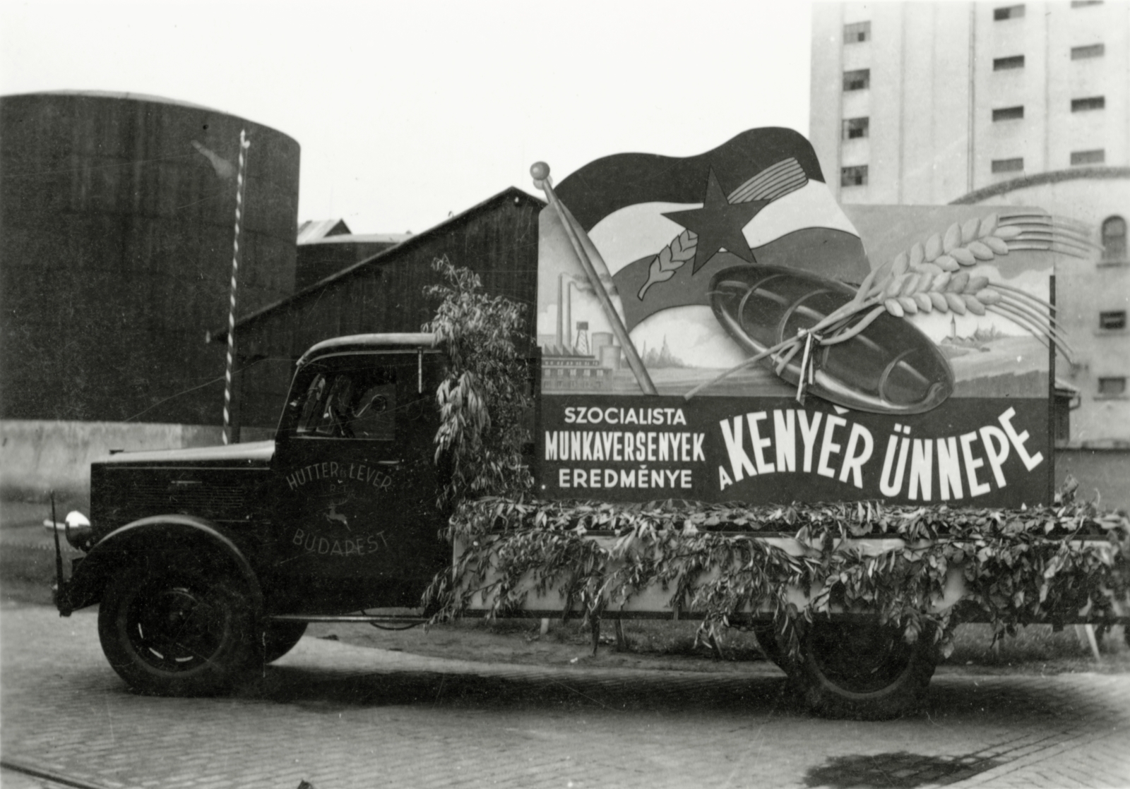 Hungary, Budapest XV., Horváth Mihály utcai gyárterület, háttérben a Hutter és Lever Rt. Olajgyár (később Rákospalotai Növényolajgyár) silója., 1949, Várkonyi Ádám, flag, political decoration, loaf of bread, Budapest, Fortepan #94540