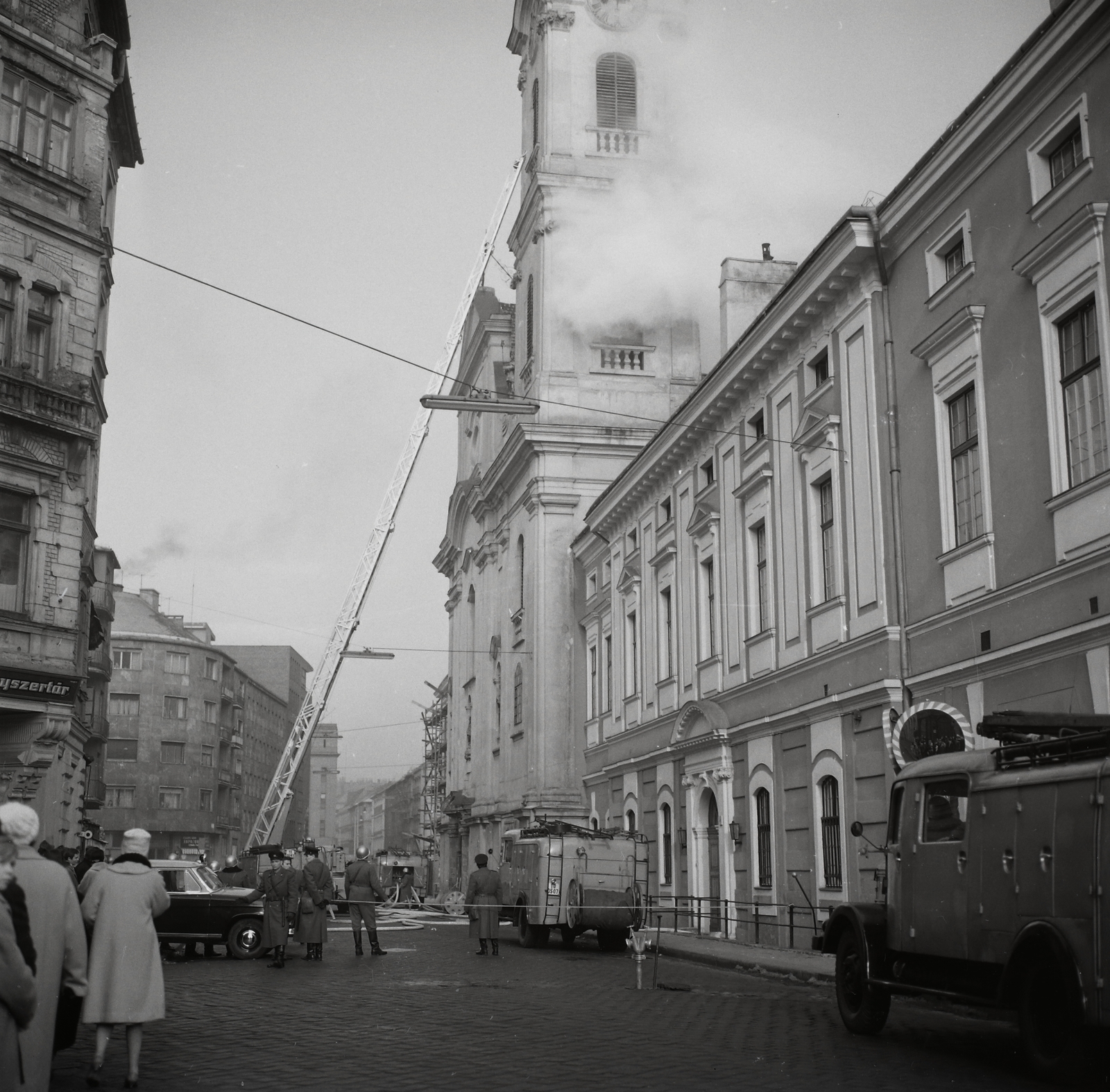 Hungary, Budapest I., Fő utca a Batthyány tér felől nézve, jobbra a Szent Ferenc sebei templom és az egykori ferences kolostor., 1964, Kotnyek Antal, church, cop, firefighter, hooker-ladder, Budapest, fire truck, Fortepan #96360