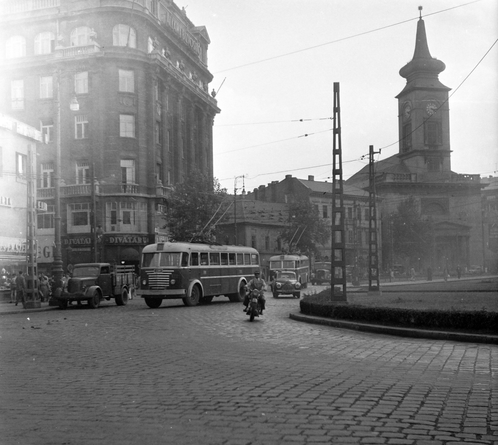 Magyarország, Budapest IX., Kálvin tér északi oldala az Üllői út és a Ráday utca torkolatával, jobbra a református templom., 1954, UVATERV, forgalom, cégtábla, motorkerékpár, teherautó, utcakép, trolibusz, lámpaoszlop, kockakő, Skoda 1101/1102 Tudor, Budapest, Phänomen-márka, Phänomen Granit, Fortepan #96629