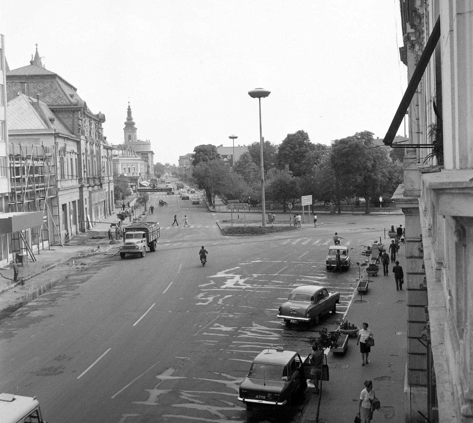 Magyarország, Nyíregyháza, Dózsa György utca, balra a Korona szálló, szemben a Kossuth tér. Háttérben a Luther (Felszabadulás) téren álló evangélikus templom., 1971, UVATERV, járókelő, teherautó, utcakép, életkép, taxi, GAZ M21 Volga, taxiállomás, rendszám, Polski Fiat 125p, virágtartó, UFO-lámpa, FSO Warszawa, Fortepan #98156