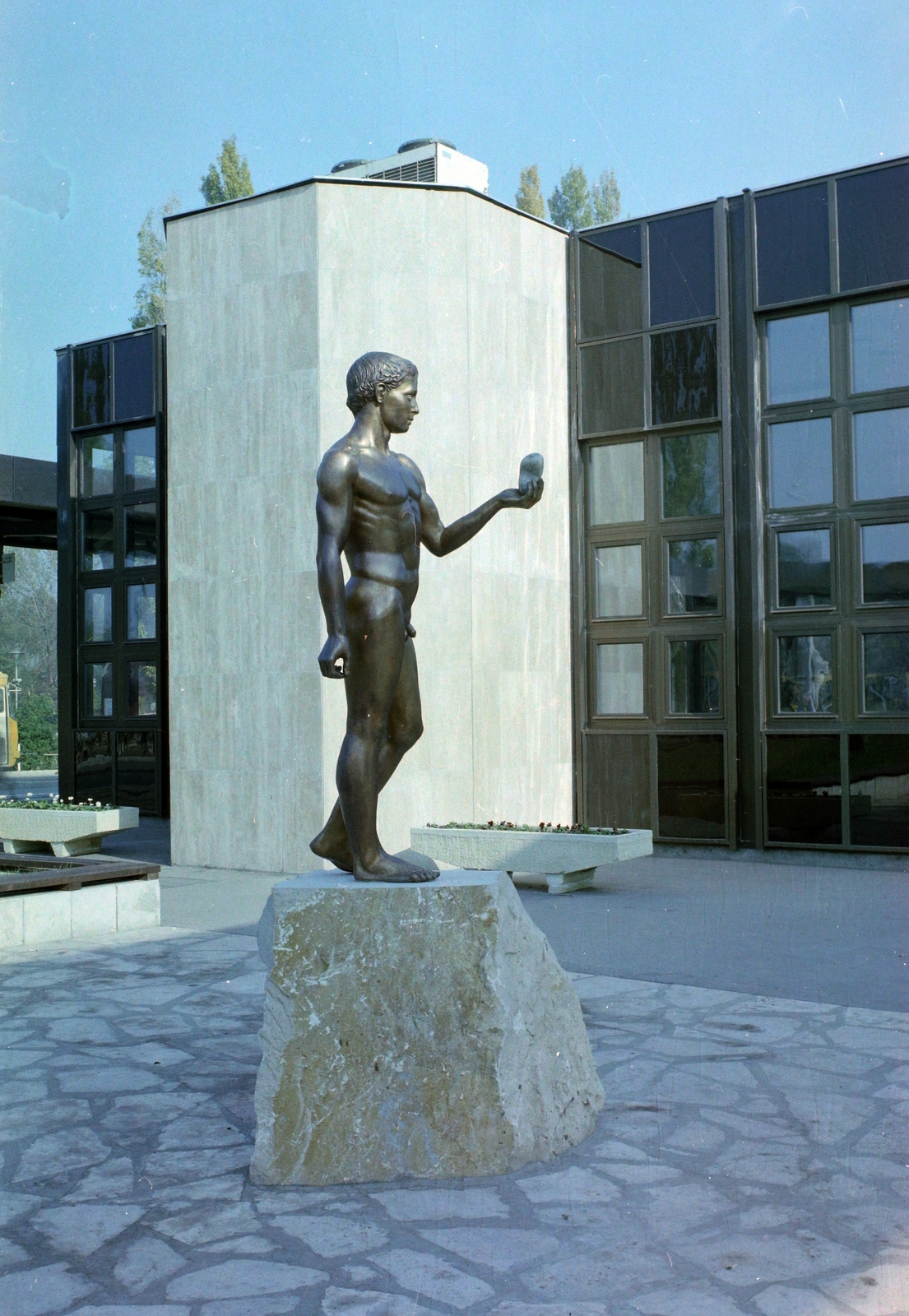 Magyarország,Balaton, Siófok, Fő utca, autóbusz-állomás, a Kavicsot tartó fiú című szobor (Csíkvári Péter, 1983)., 1985, UVATERV, színes, szobor, autóbuszállomás, meztelen alak, autóbusz, Ikarus-márka, Fortepan #99482