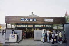 Magyarország,Balaton, Siófok, Millennium park (Váradi Adolf tér), Utasellátó büfé. A háttérben balra az autóbusz-állomás, jobbra a Sarlós Boldogasszony-templom tornya., 1974, Bauer Sándor, színes, büfé, utasellátó, Eskimo-márka, Fortepan #109835