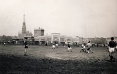 Hungary, Budapest XIV., előterében a Magyar Hockey Club (MHC) gyeplabdaklubjának az korábbi lóversenytér területén, a Dózsa György (Aréna) út és a Verseny utca találkozásánál kialakított pályája látható. Háttérben a Szent Domonkos (később Récsei) autóbuszgarázs, balra a Rózsafüzér Királynéja-templom a Thököly úton., 1930, Buzinkay Géza, field hockey, Budapest, bus garage, Fortepan #114666