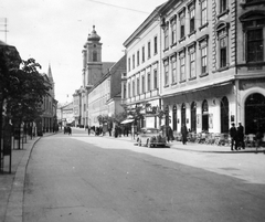 Magyarország, Székesfehérvár, Fő (Nádor) utca, szemben a Nepomuki Szent János-templom és rendház., 1940, Gyöngyi, templom, német gyártmány, Opel-márka, utcakép, életkép, barokk-stílus, üzletportál, katolikus, kávéház, automobil, Opel Kadett, Paul Hatzinger-terv, Fortepan #11472