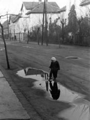 Magyarország, Budapest XV., Szűcs István (Doktor Sándor) utca, szemben a 18. és 20. számú ház., 1958, Móra András, pocsolya, Budapest, kíváncsiság, gyerek, tükröződés, Fortepan #114965