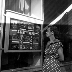 Magyarország, Budapest VII., a felvétel a Károly (Tanács) körút 21., a Magyar Fotó Állami Vállalat kirendeltsége előtt készült., 1955, Aradi Péter, Szenczi Mária, Budapest, képarány: négyzetes, pöttyös ruha, faliújság, kép a képben, Fortepan #117345