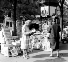 Franciaország, Párizs, Boulevard Saint-Germain, újságárus a Rue de l'Ancienne Comédie sarkánál., 1959, Aradi Péter, Szenczi Mária, nők, pavilon, újságárus, háttal, szoknya, olvasás, Fortepan #117552