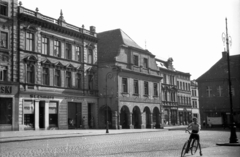 Lengyelország, Leszno, Rynek, a város főtere a Városháza előtt. Szemben az ulica Waleriana Wróblewskiego sarkán álló ház. Jobbra az ulica Leszczynkisch, 1947, Bogdan Celichowski, utcakép, utcai lámpa, üzletportál, kerékpár, Fortepan #119148