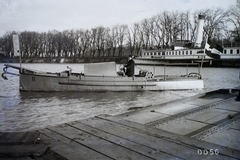 Magyarország, Óbuda, Budapest III., Óbudai Hajógyár, katonai, kétcsavaros vontató motoroshajó a Hajógyári-öbölben. Háttérben a DDSG Wien (1912) személyszállító gőzhajó. Leltári jelzet: MMKM TFGY 2017.2.512., 1916, Magyar Műszaki és Közlekedési Múzeum / Történeti Fényképek Gyűjteménye / Óbudai Hajógyár gyűjteménye, gőzhajó, horgony, Budapest, Fortepan #122246