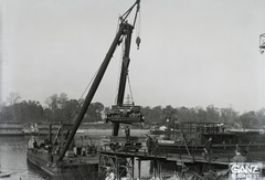 Magyarország, Budapest XIII., Újpesti-öböl, Ganz és Tsa. Villamossági-, Gép-, Waggon- és Hajógyár Rt. Az Újpest (1906) úszódarun egy 400 HP Jendrassik motor, a DTRT Tisza (1937) Duna-tengerjáró áruszállító hajóba történő beemelésekor. Leltári jelzet: MMKM TFGY 2017.1.209., 1937, Magyar Műszaki és Közlekedési Múzeum / Történeti Fényképek Gyűjteménye / Ganz gyűjtemény, úszódaru, Budapest, Fortepan #122604