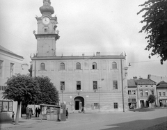 Szlovákia, Késmárk, Hlavné námestie (korábban Kossuth Lajos utca), szemben a Városháza., 1956, Gyöngyi, Csehszlovákia, vörös csillag, újságárus, középület, taxiállomás, toronyóra, Fortepan #12701