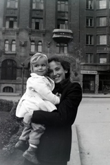 Magyarország, Budapest VIII., Horváth Mihály (Mária Terézia) tér, a háttérben balra a József Telefonközpont épülete., 1946, Barna Imre, Budapest, kézben tartani, hölgy, mosoly, kisfiú, cégtábla, Fortepan #133379