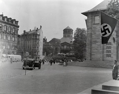 Németország, Bayreuth, Luitpoldplatz (ekkor Hans Schemm Platz), középen a Régi Kastély (Altes Schloss Bayreuth) tornya, jobbra a Német Oktatási Ház (Haus der Deutschen Erziehung)., 1936, Révay Péter, horogkereszt, nácizmus, kerékpár, Fortepan #136426