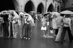 Csehország, Prága, a turisták az Óváros téren (Staromestske namesti) állnak és
az Orjol-t, a prágai városháza oldalán található óraművet nézik., 1983, Vészi Ágnes, Csehszlovákia, eső, átkulcsolt derék, csúcsív, esőkabát, leselkedő, Fortepan #136886