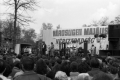 Magyarország, Városliget, Budapest XIV., május 1-i Népszabadság - fórum. A Magyar Rádió Szabó család című sorozatának nyilvános felvétele. A mikrofonoknál Őze Lajos és Horváth Tivadar színművészek, a konténer előtt Benkő Péter színművész ül., 1980, Szalay Zoltán, május 1, színpad, dob, hangfal, reflektor, Népszabadság, Budapest, cintányér, Fortepan #138848