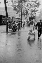 Magyarország, Budapest VI., Teréz (Lenin) körút az Aradi utcától az Oktogon (November 7. tér) felé nézve., 1955, Barbjerik Ferenc, Budapest, kézikocsi, esernyő, olvasás, újság, vesszőkosár, esőkabát, trafik, pad, trolibusz, Fortepan #148374