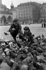 Lengyelország, Krakkó, Rynek Glówny a város főtere, balra a Posztócsarnok (Sukiennice)., 1966, Barbjerik Ferenc, kislány, apa, madáretetés, galamb, Fortepan #148757