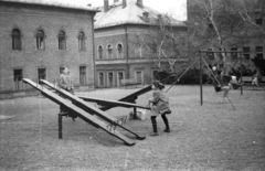 Hungary, Budapest XII., Margaréta utcai játszótér. Háttérben a Rendőr Tiszthelyettesi Iskola (később BM Nemzetközi Oktatási Központ) épületei, jobbra a Kerületi Tanács (később Polgármesteri Hivatal)., 1973, Ebner, seesaw, swing, Budapest, Fortepan #151822