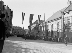 Magyarország, budai Vár, Budapest I., Tárnok utca a Dísz tér felől nézve., 1948, Magyar Rendőr, zászló, utcakép, felvonulás, zenekar, közönség, katonazenekar, lámpaoszlop, katona, kard, épületkár, kockakő, Budapest, Fortepan #16442