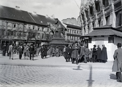 Magyarország, Budapest V.,Budapest VI., Deák Ferenc tér, szemben a Bajcsy-Zsilinszky (Vilmos császár) út. Balra a Kemnitzer ("Két török") ház, jobbra az Anker-ház. Kőzépen a Nemzeti áldozatkészség szobra (Sidló Ferenc, 1915.). A szobor fából készült, amelyre megszabott összeg fejében fémlemezkéket szögelhettek az adományozók., 1916, Fortepan, Budapest, Fortepan #170907