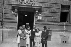 Magyarország, Budapest XIV., Pétervárad utca 2., a felvétel a kerületi Elöljáróság (később Zuglói Polgármesteri Hivatal) előtt készült., 1946, Sattler Katalin, Budapest, nyakkendő, öltöny, úriember, hölgy, csoportkép, kosztüm, kalap, nyíl, vészkijárat, postaláda, Fortepan #171036