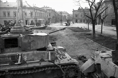 Magyarország, Székesfehérvár, Zichy liget (Vilmos császár tér), szemben a Fő (Nádor) utca. A kép jobb szélén a Velence (előtte és később Magyar Király) szálló oldala, tőle balra a Vörösmarty Szinház épülete. A kép előterében bal oldalt a Szentháromság-szobor látható., 1945, Vörös Hadsereg, harckocsi, járműroncs, Panzerkampfwagen IV, Fortepan #175215