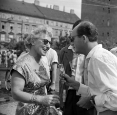 Magyarország, Budapest V., Vigadó tér az Apáczai Csere János utca a felé nézve, jobbra a a Duna Szálló északi fala. A "riporter" Brachfeld Siegfried konferanszié., 1960, Szalay Zoltán, Budapest, hölgy, mikrofon, ékszer, nyári ruha, Fortepan #190489