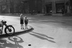 Magyarország, Budapest VIII., Baross utca, a mára megszűnt Beniczky Lajos utcánál, ma a Szigony utca házaihoz lehet bejutni. Szemben a háttérben a Vasas köz., 1956, Kriss Géza, Budapest, utcakép, kisfiú, kislány, gyerekek, várakozás, fény-árnyék, járda, Fortepan #191918