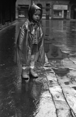 Hungary, Budapest VIII., a mára megszűnt Beniczky Lajos utca, itt ma a Szigony utca házaihoz lehet itt bejutni. Háttérben a Baross utca., 1956, Kriss Géza, Budapest, kid, store display, raincoat, pavement, puddle, Fortepan #191924