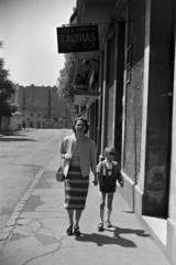 Magyarország, Budapest VIII., a mára megszűnt Beniczky Lajos utca a Bókay János utca felé nézve. Jobbra a 3-5. számú házban az Otthon mozi., 1958, Kriss Géza, Budapest, anya, kézenfogva, kisfiú, cégtábla, Kályhásmester, Fortepan #191995