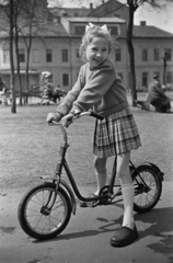 Magyarország, Budapest VIII., Horváth Mihály tér, háttérben a Baross utca 69. számú ház térre néző frontja., 1958, Kriss Géza, Budapest, kislány, kerékpár, mosoly, rakott szoknya, Fortepan #192007